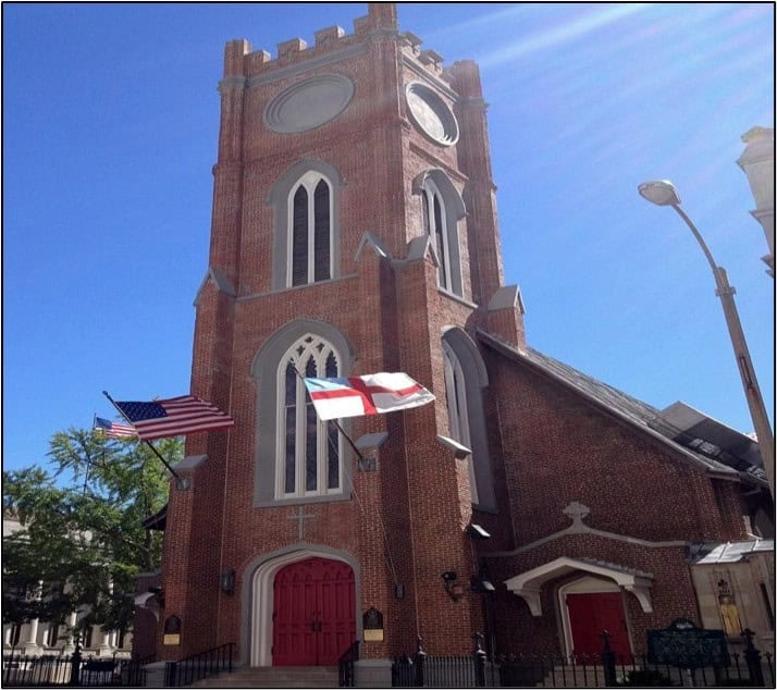 Memphis Heritage Inc. historic church with a tall brick tower, American and Alabama flags, and vibrant red doors, exemplifying Memphis's architectural and cultural heritage.