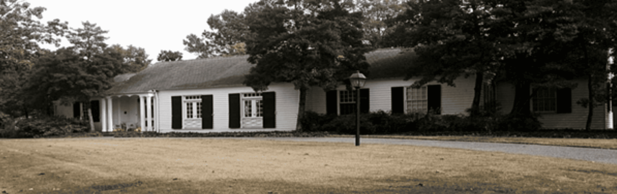 Memphis Heritage Inc. historic building with white wooden exterior, black window shutters, surrounded by mature trees and a well-maintained lawn, representing Memphis's rich cultural and architectural history.
